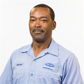 Man in light blue work shirt, smiling slightly, with a name tag that reads