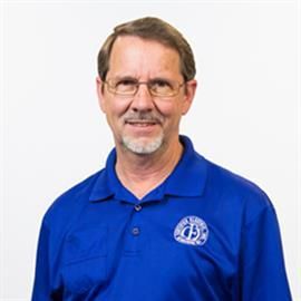 Man wearing glasses and blue polo shirt smiles.