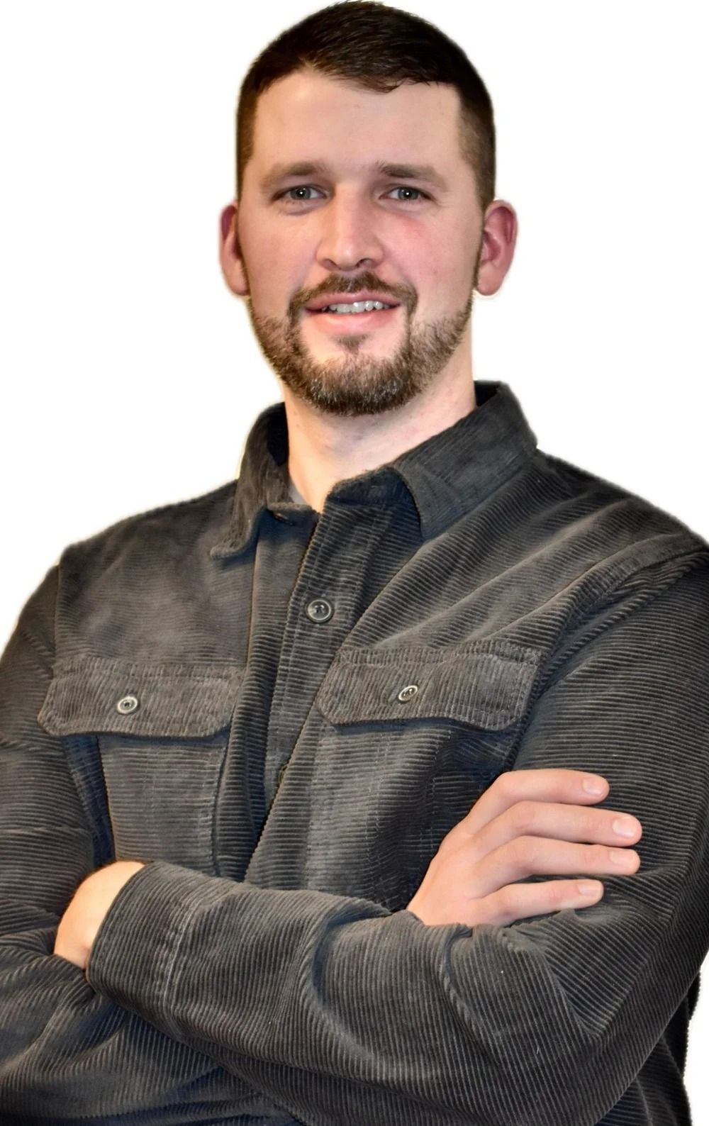 Man with short brown hair and beard, arms crossed, wearing gray corduroy shirt, smiling.