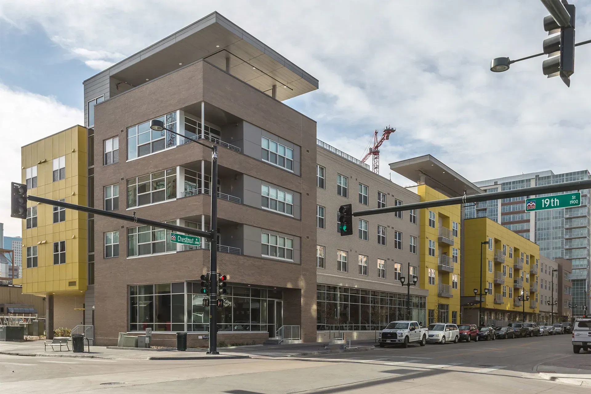 Modern apartment building with brown, yellow, and gray facades at a city street corner