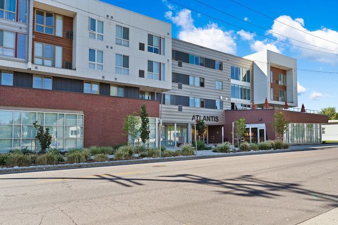 Modern hotel building with white and brick facade, large windows, and a covered entrance under a blue sky