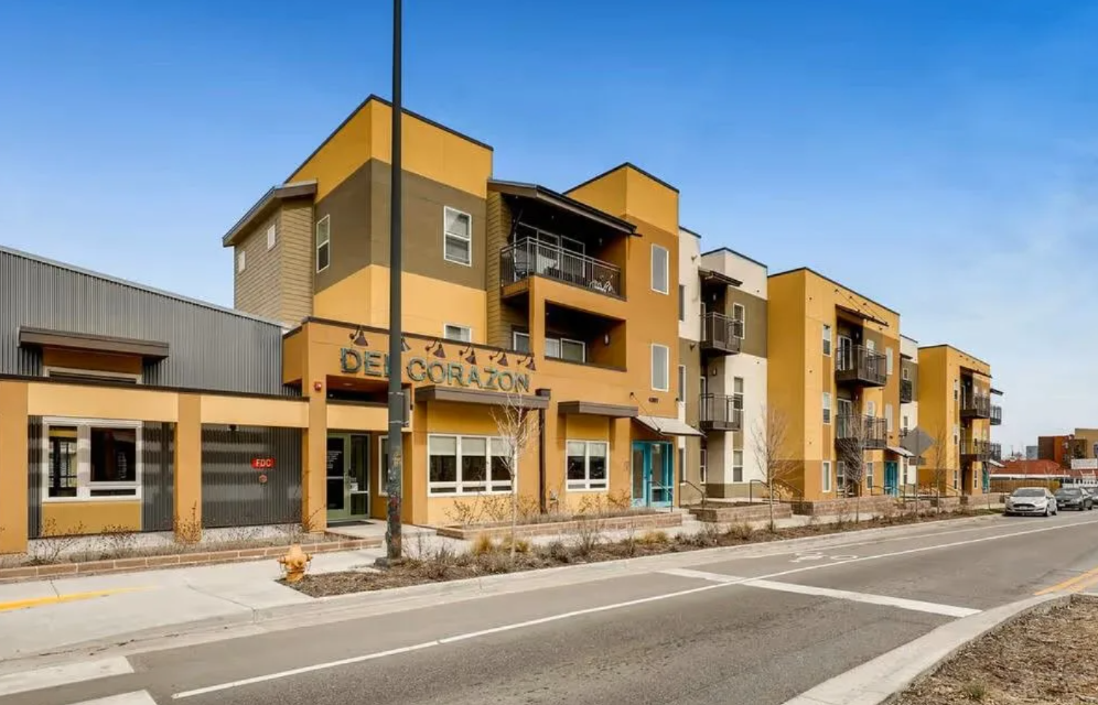 Modern apartment building with storefronts along a street on a sunny day