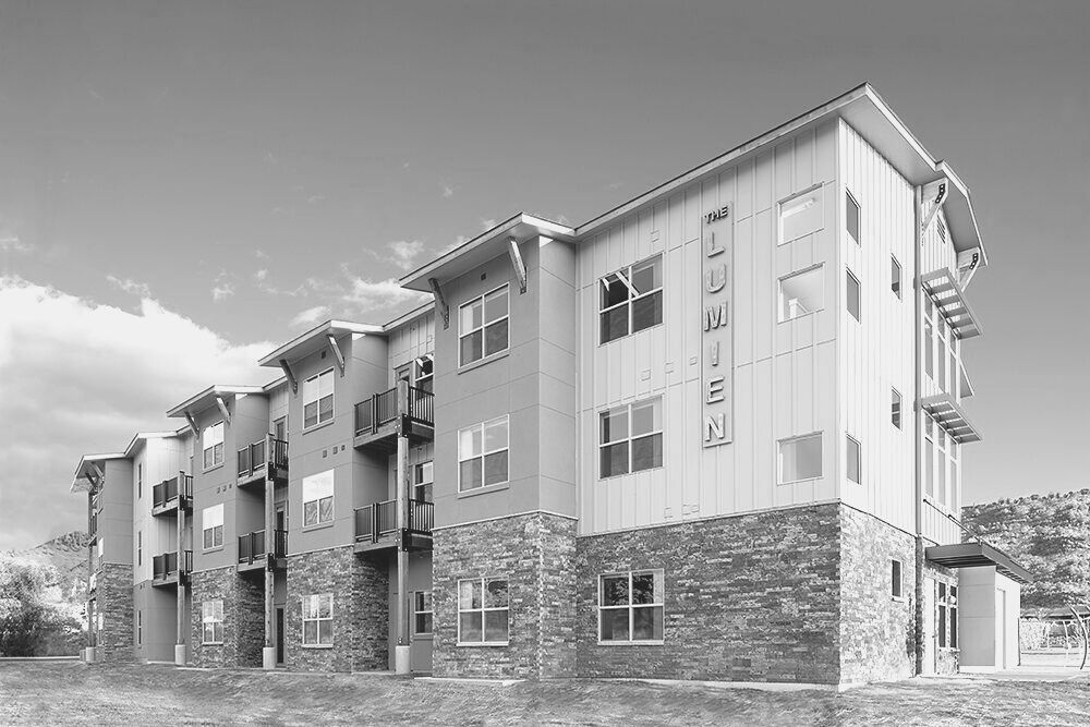 Three-story apartment building with stone facade and balconies under a cloudy sky