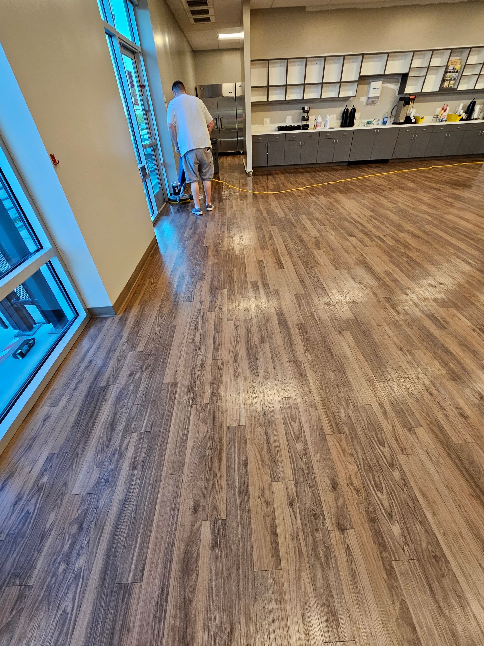 A man is standing on a wooden floor in a room.