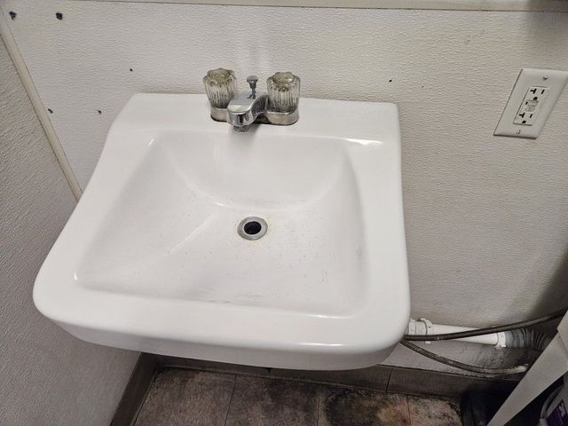 A white sink is hanging on a wall in a bathroom.