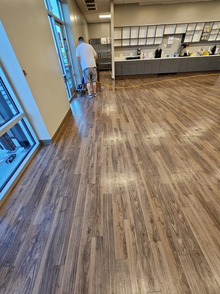 A man is standing on a wooden floor in a room.