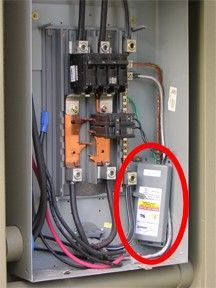 Electrical panel with wires and breakers; a surge protector is circled in red.