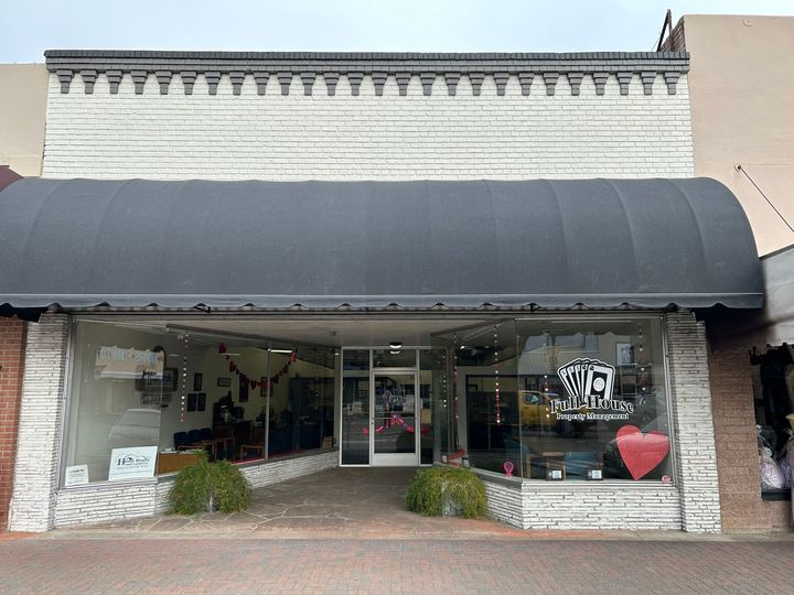 A store front with a black awning and a heart in the window.