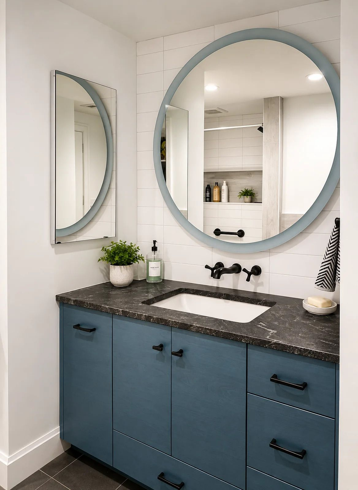 Modern white bathroom with wood vanity, oval mirrors, soaking tub, and frosted glass door