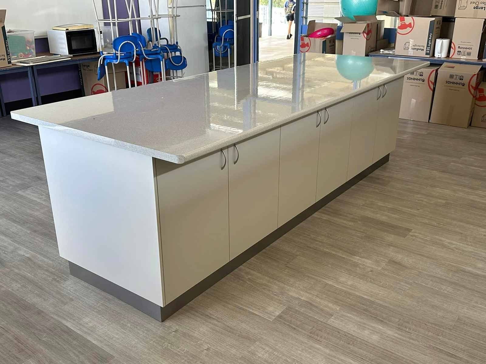 Long Kitchen Island With White Countertop and Beige Cabinets — Keilbach Kitchens in Cairns, QLD