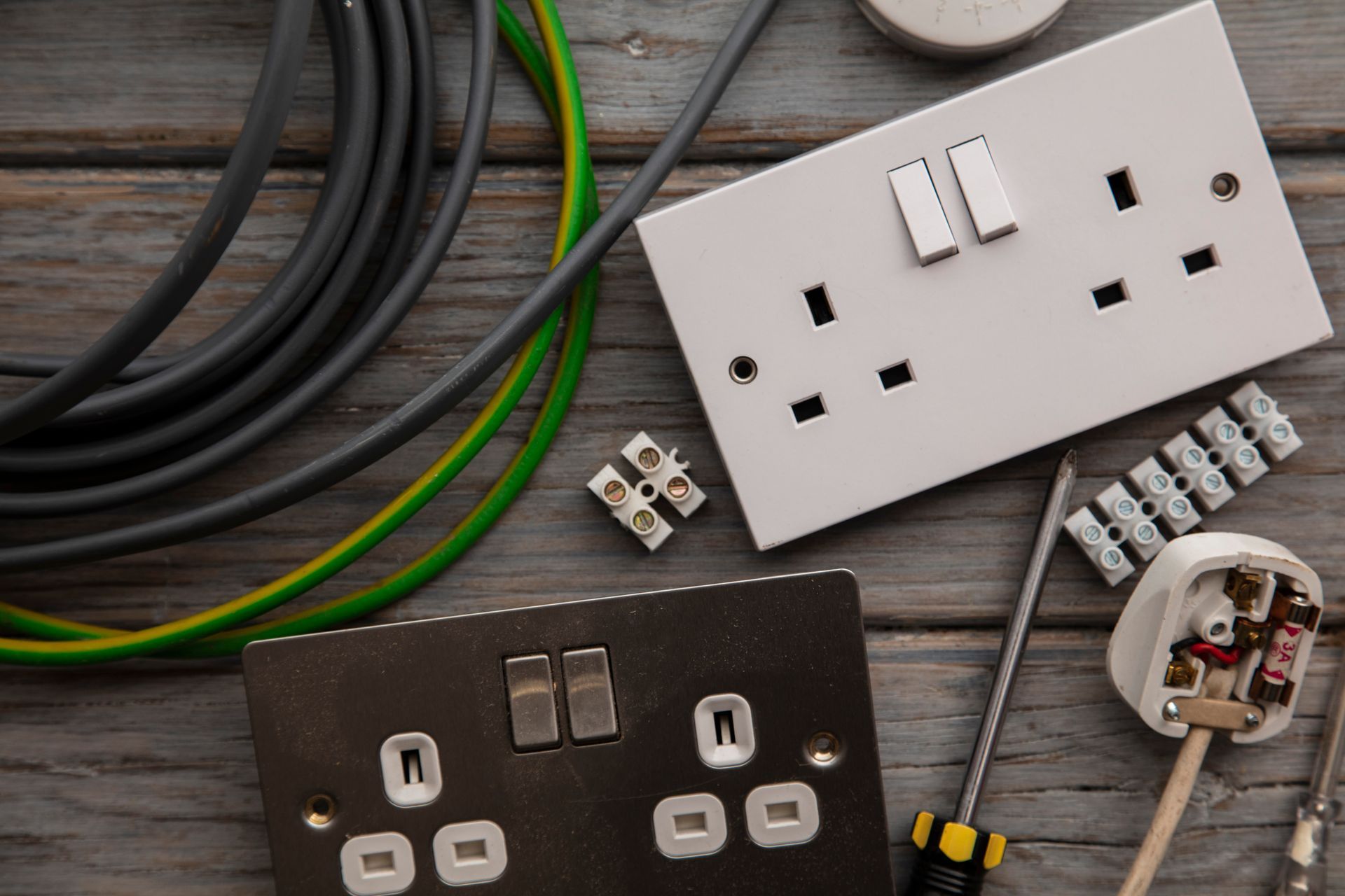 Electrical components: outlets, wires, and tools on a wooden surface, ready for installation.