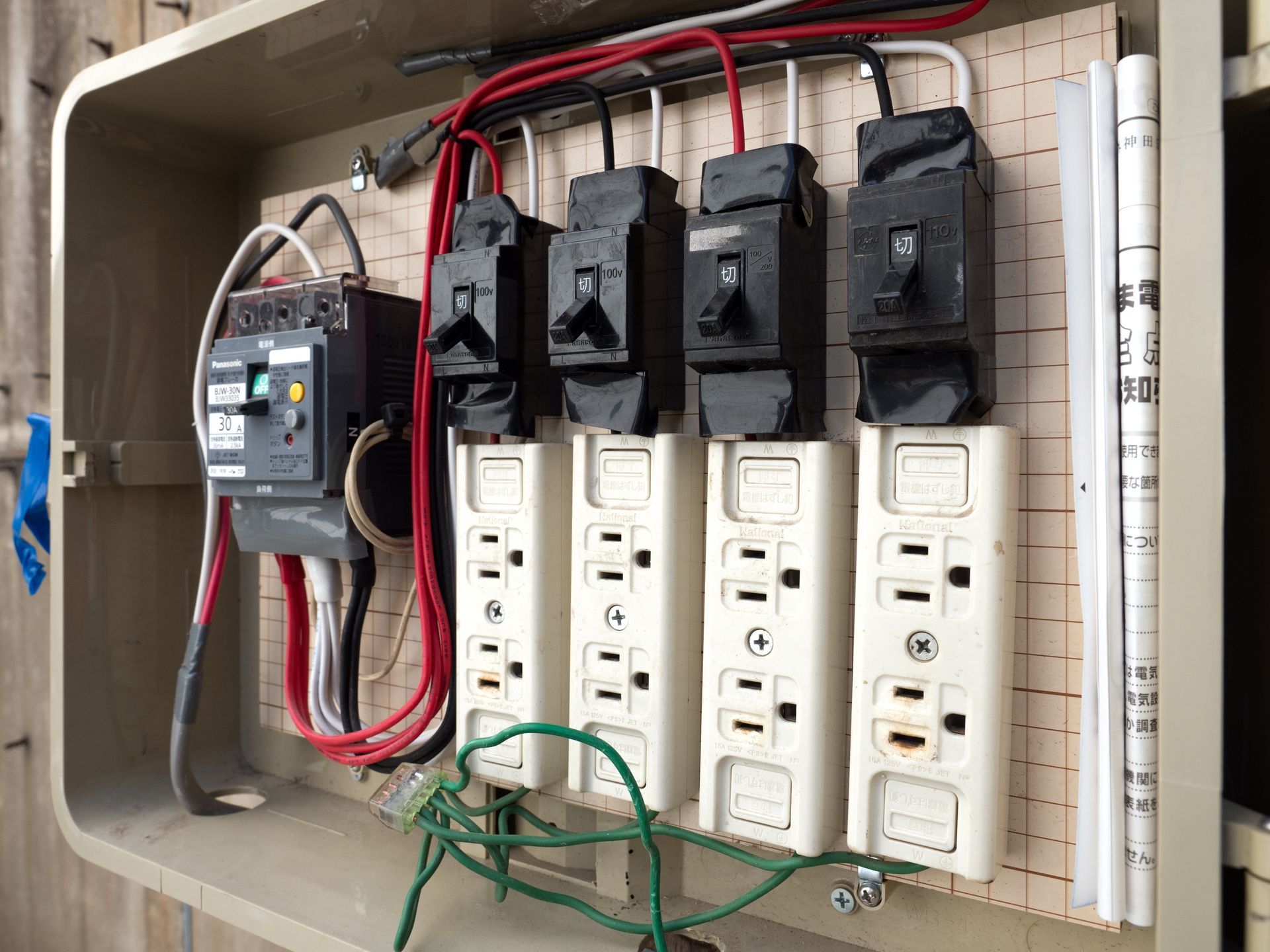Electrical box with circuit breakers and outlets, wiring visible.