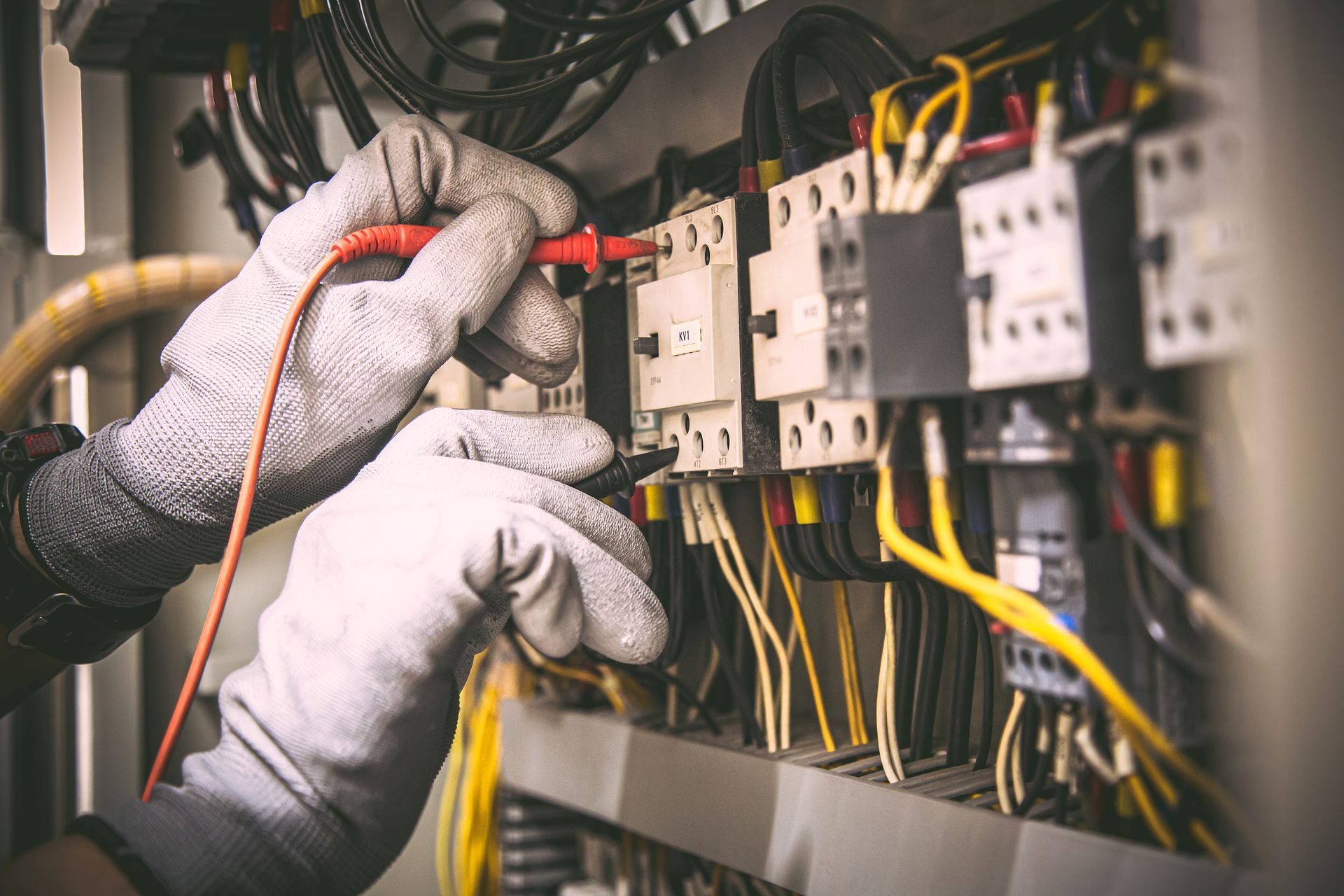 Electrician checking wiring connections in an electrical cabinet with insulated tools