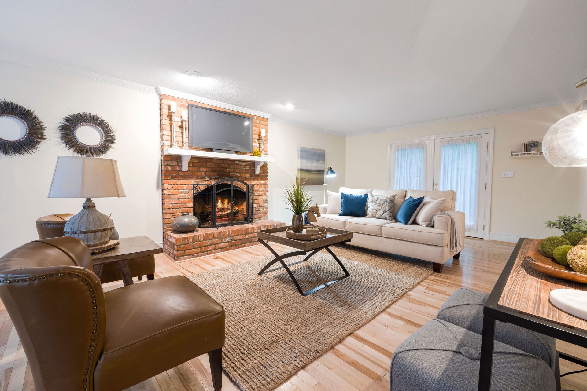 Bright living room with a fireplace, beige sofa, coffee table, and large windows.