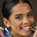 Une femme portant une carte kara junior tient une médaille dans sa bouche