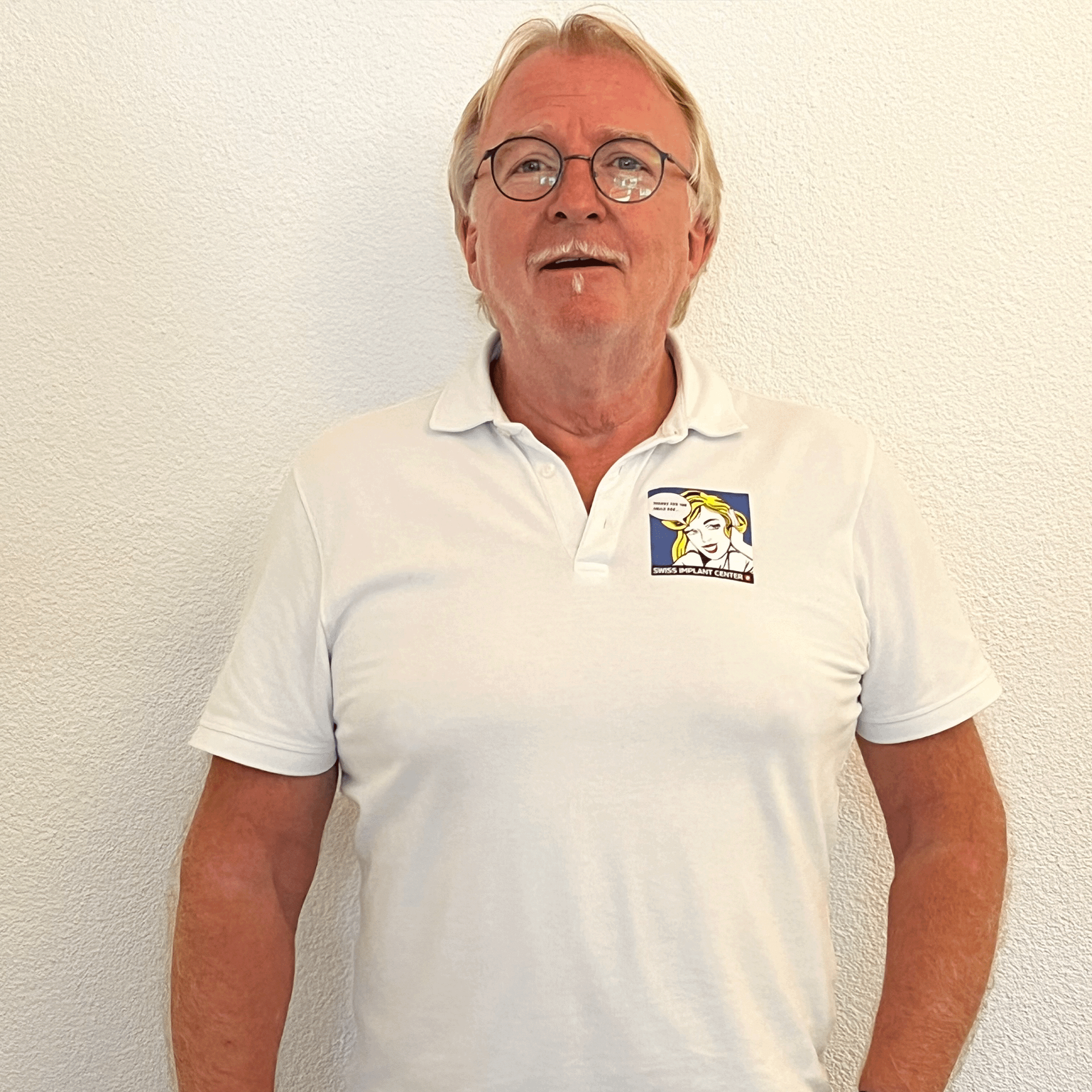 Un homme portant des lunettes et un polo blanc
