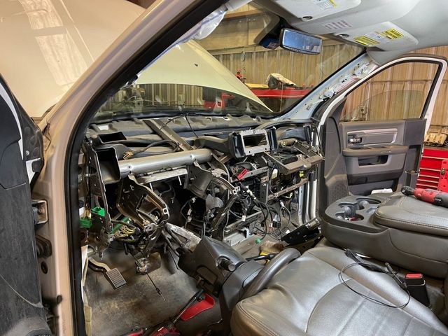 Severely damaged car interior with exposed dashboard wiring and open passenger door