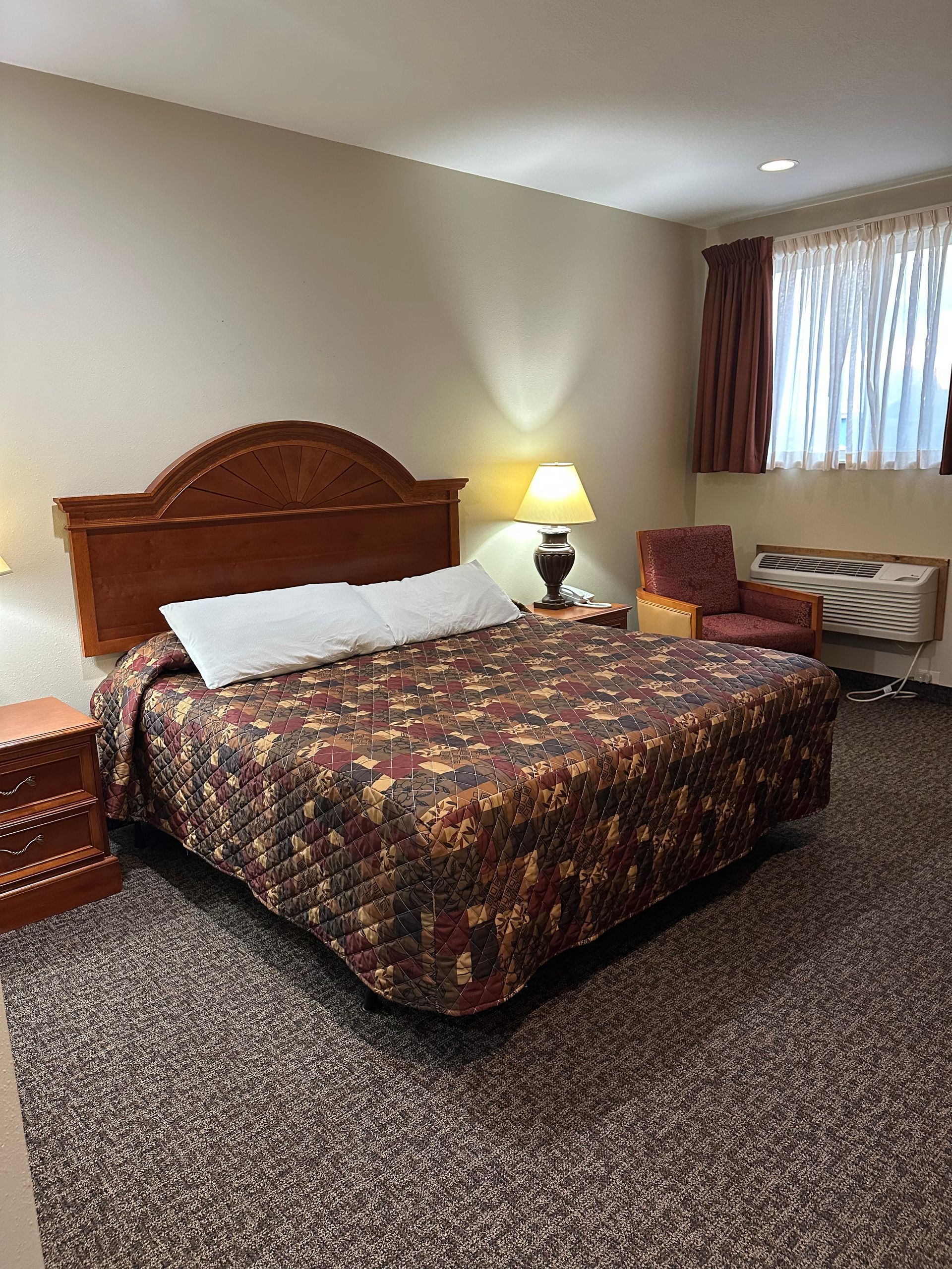 Hotel room with a bed, nightstands, a chair, and a window.