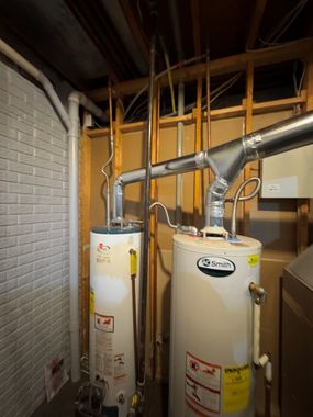 Technician repairing pipes and valves under water heater with tools and gloves