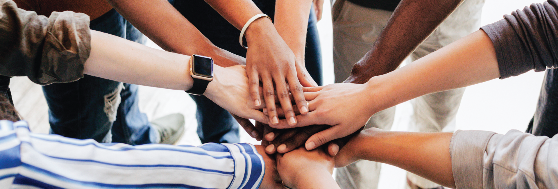 A group of people are putting their hands together in a circle.