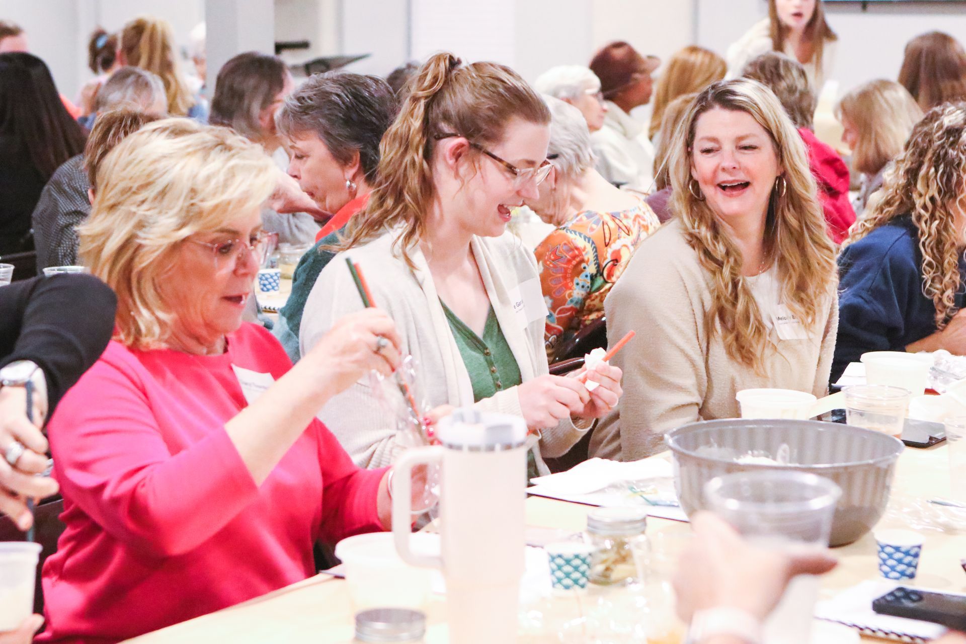 People seated at a table at a social gathering, talking and eating with drinks and serving dishes.