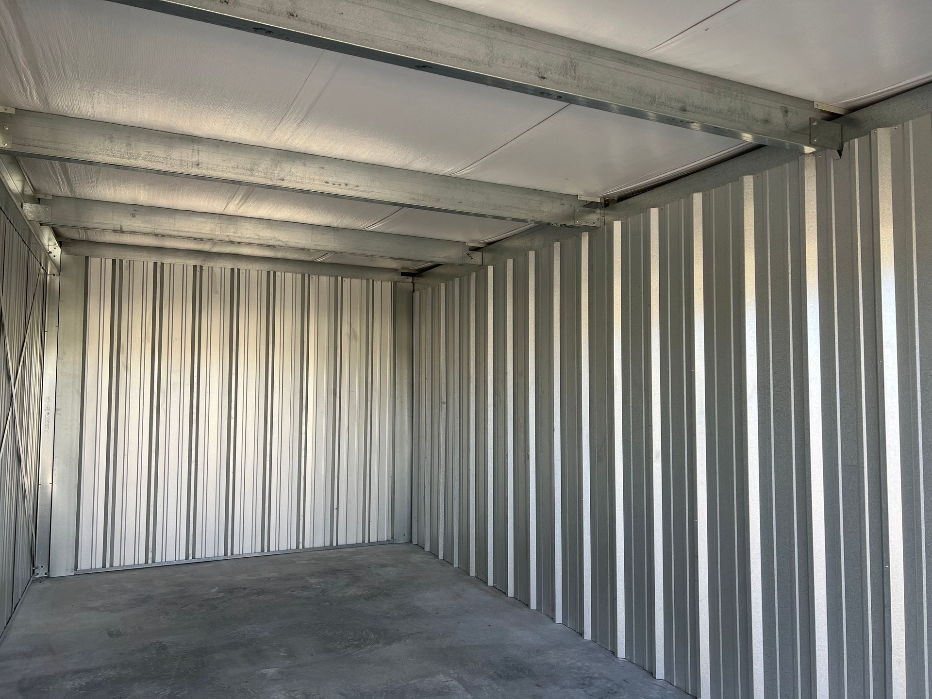 Inside of a clean self-storage with metal walls and a concrete floor.