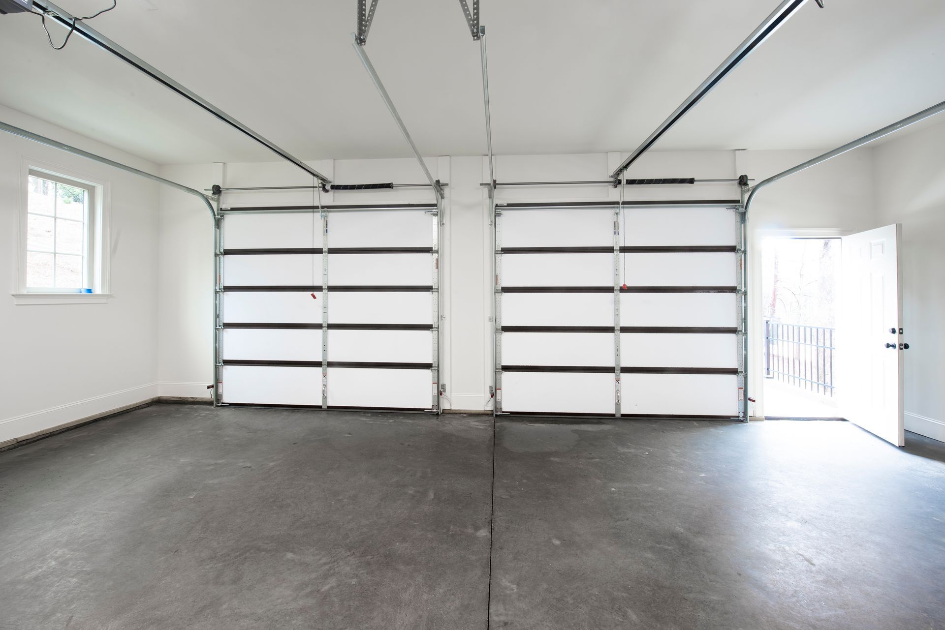 An empty garage with two garage doors and a window