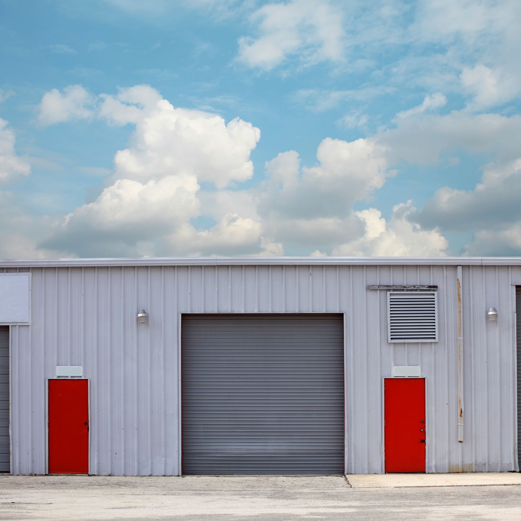 A row of garage doors with red doors and a blue sky in the background