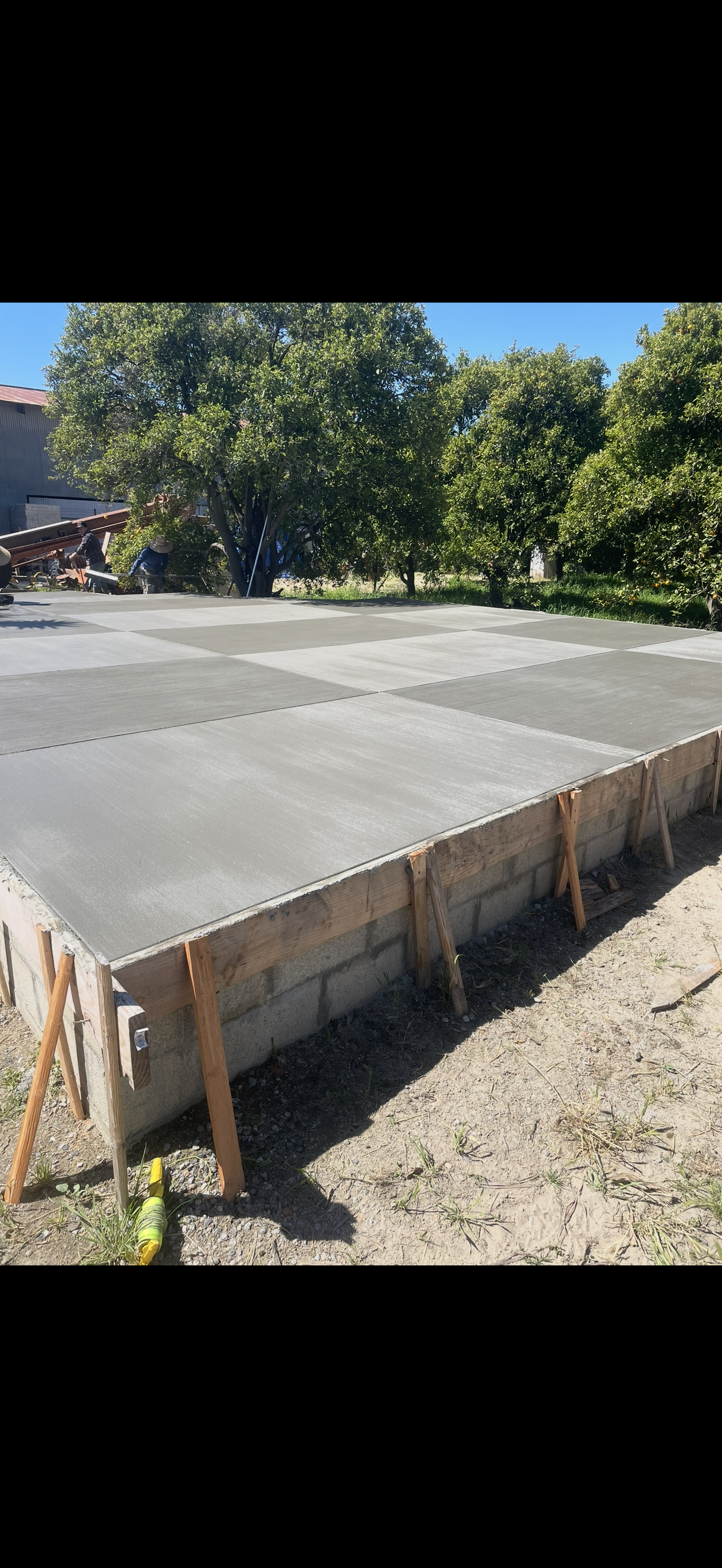 Freshly poured concrete foundation with wooden supports, outdoors.