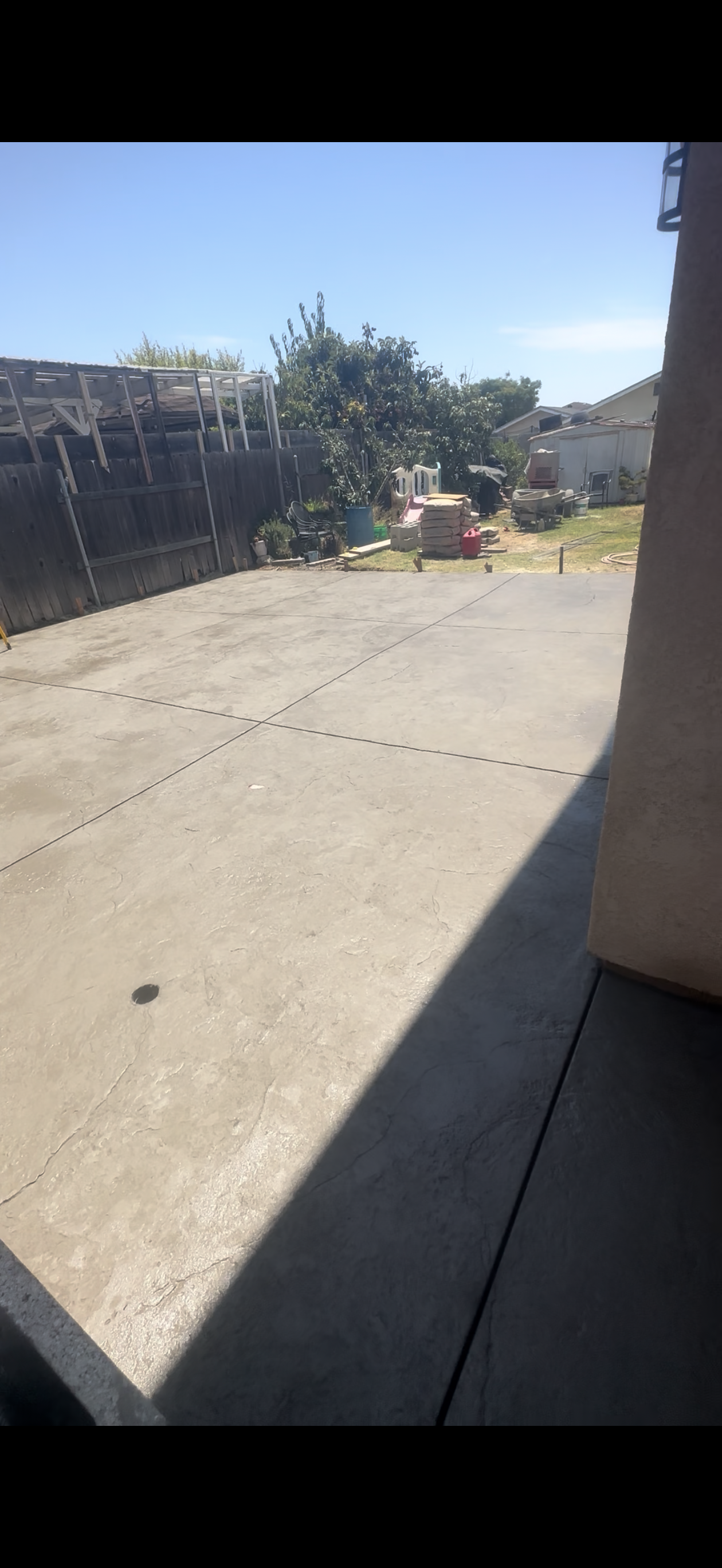 A concrete driveway on a sunny day with trees and a building in the background.