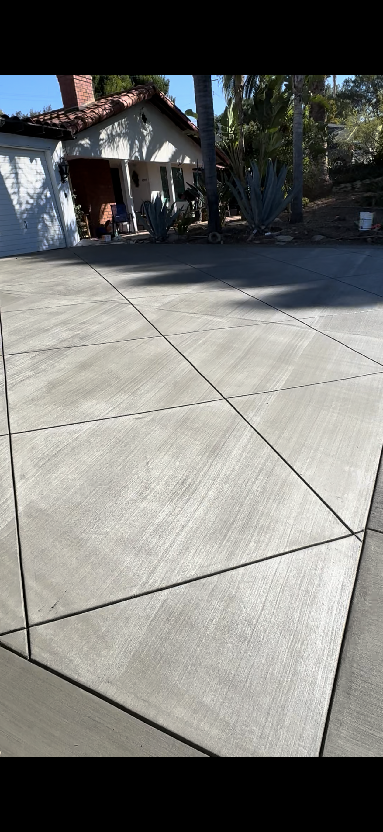 New concrete driveway with saw-cut control joints in front of a house.