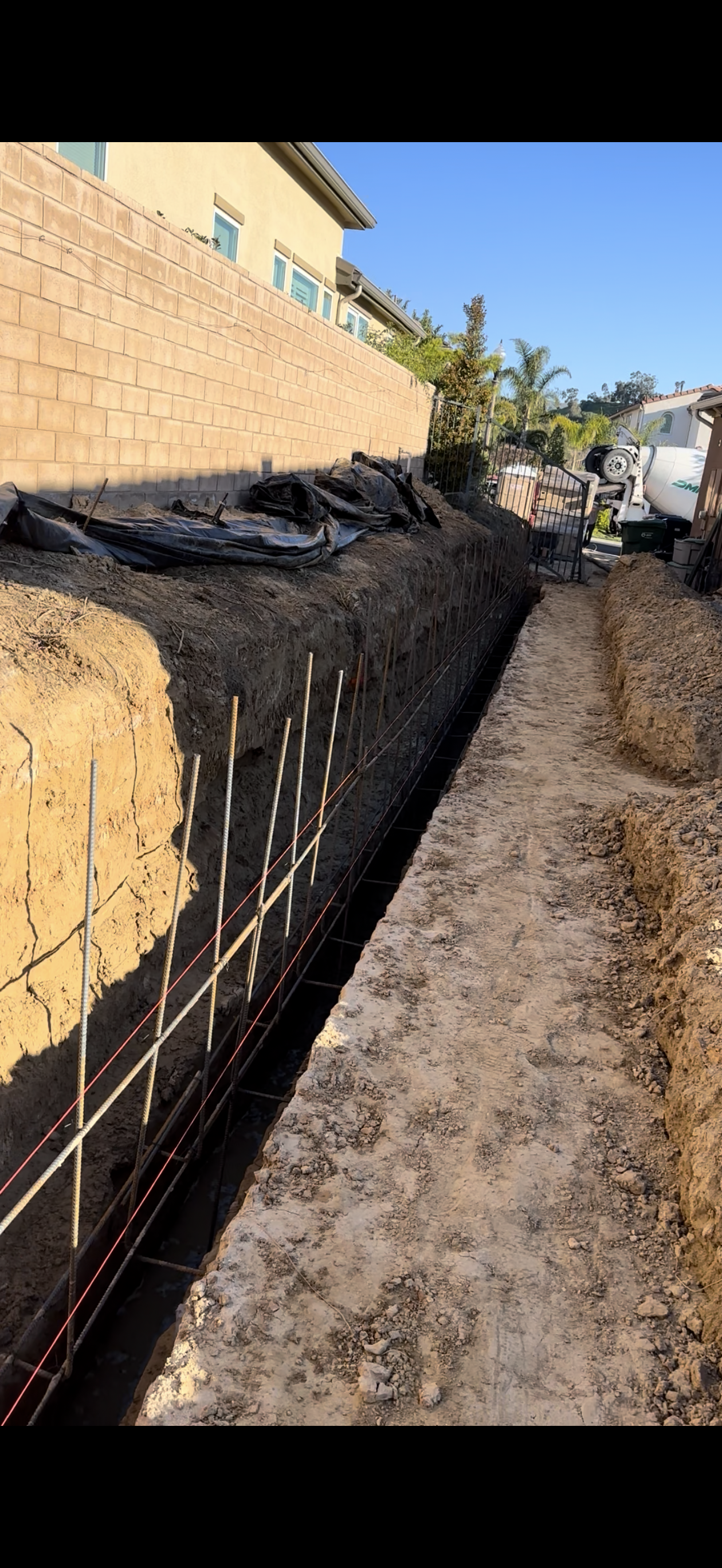 Construction site with a trench, rebar, and a retaining wall.