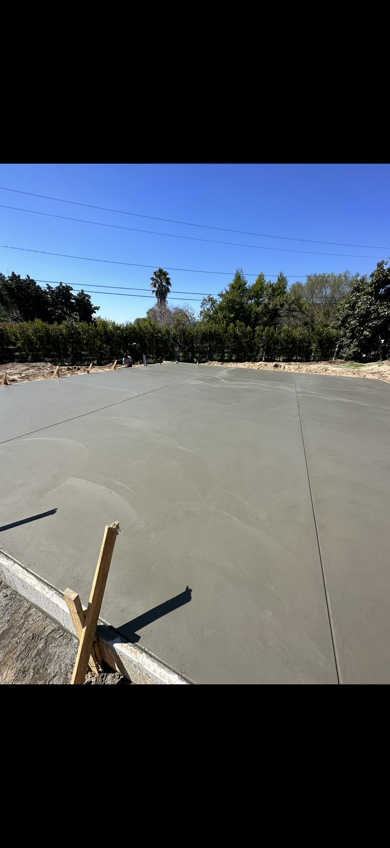 Newly poured concrete slab with construction markings and a clear blue sky above.