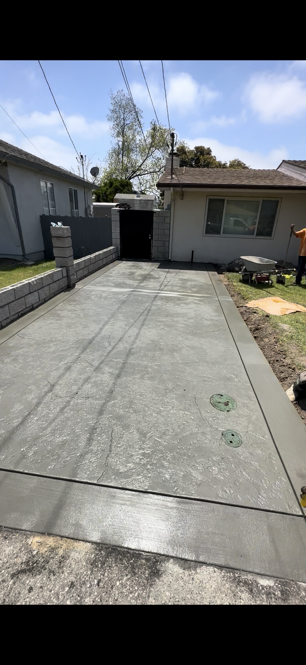 Driveway leading to a house with a concrete driveway and a gate in a neighborhood.