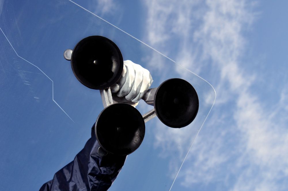 A Person Is Holding Two Suction Cups in Front of A Blue Sky — A1 Windscreens in Gunnedah, NSW