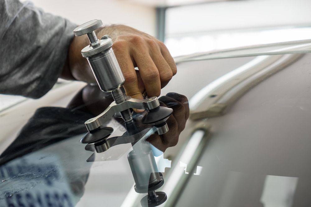A Person Is Repairing a Windshield on A Car with A Machine — A1 Windscreens in Taminda, NSW