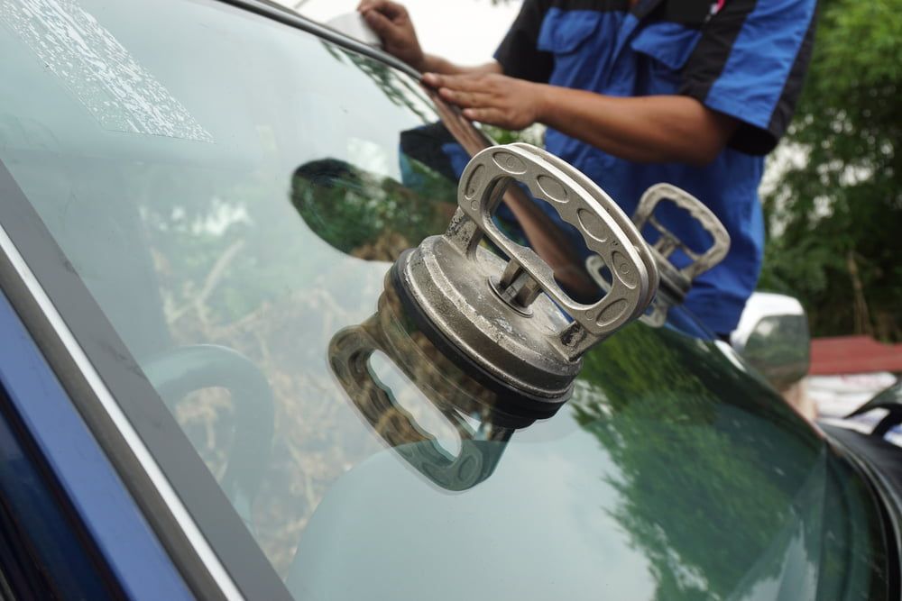 A Man Is Installing a New Windshield on A Car — A1 Windscreens in Armidale, NSW