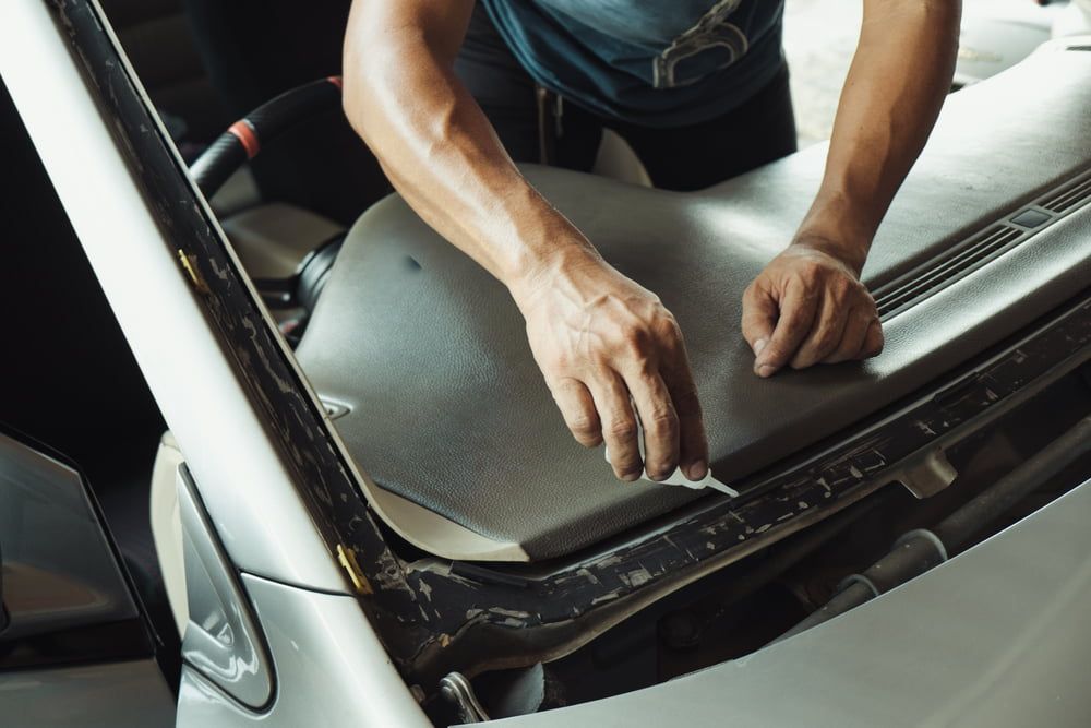 A Man Is Working on The Hood of A Car — A1 Windscreens in Armidale, NSW