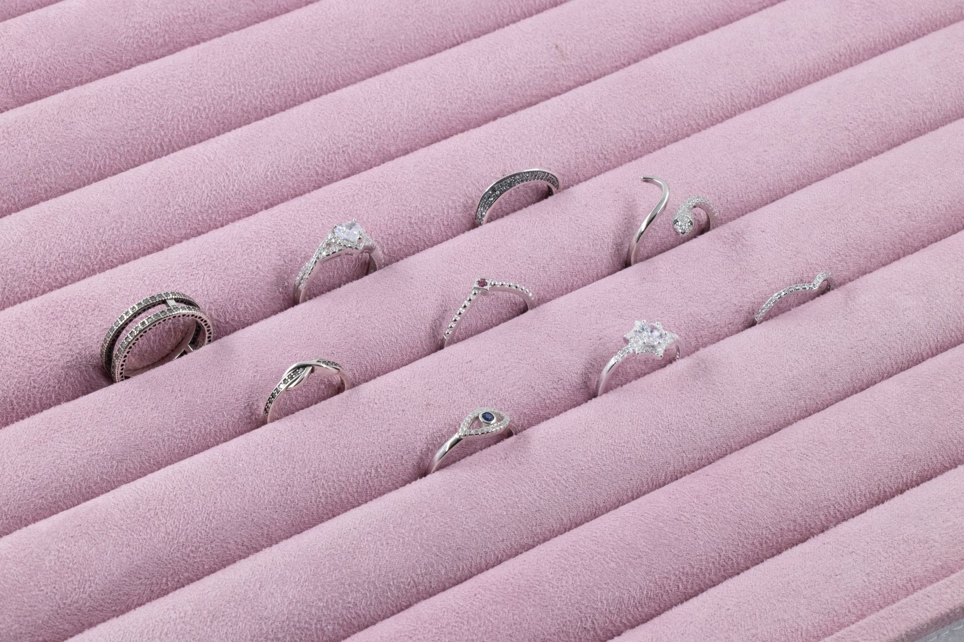 Tela rosa plisada con varios objetos diminutos parecidos a insectos en blanco y negro esparcidos por ella.