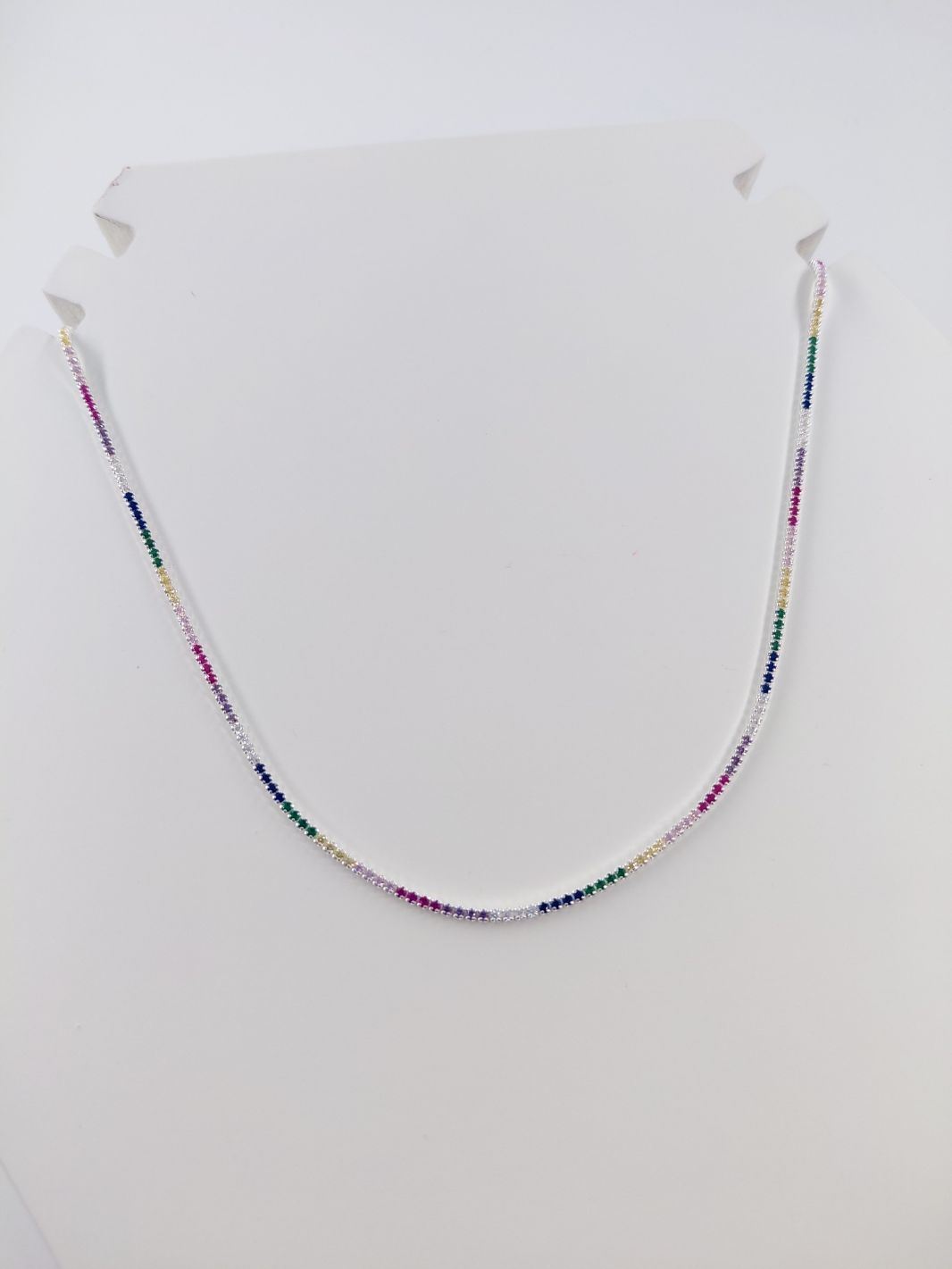Collar de cuentas de colores dispuesto en forma de U sobre un fondo claro.