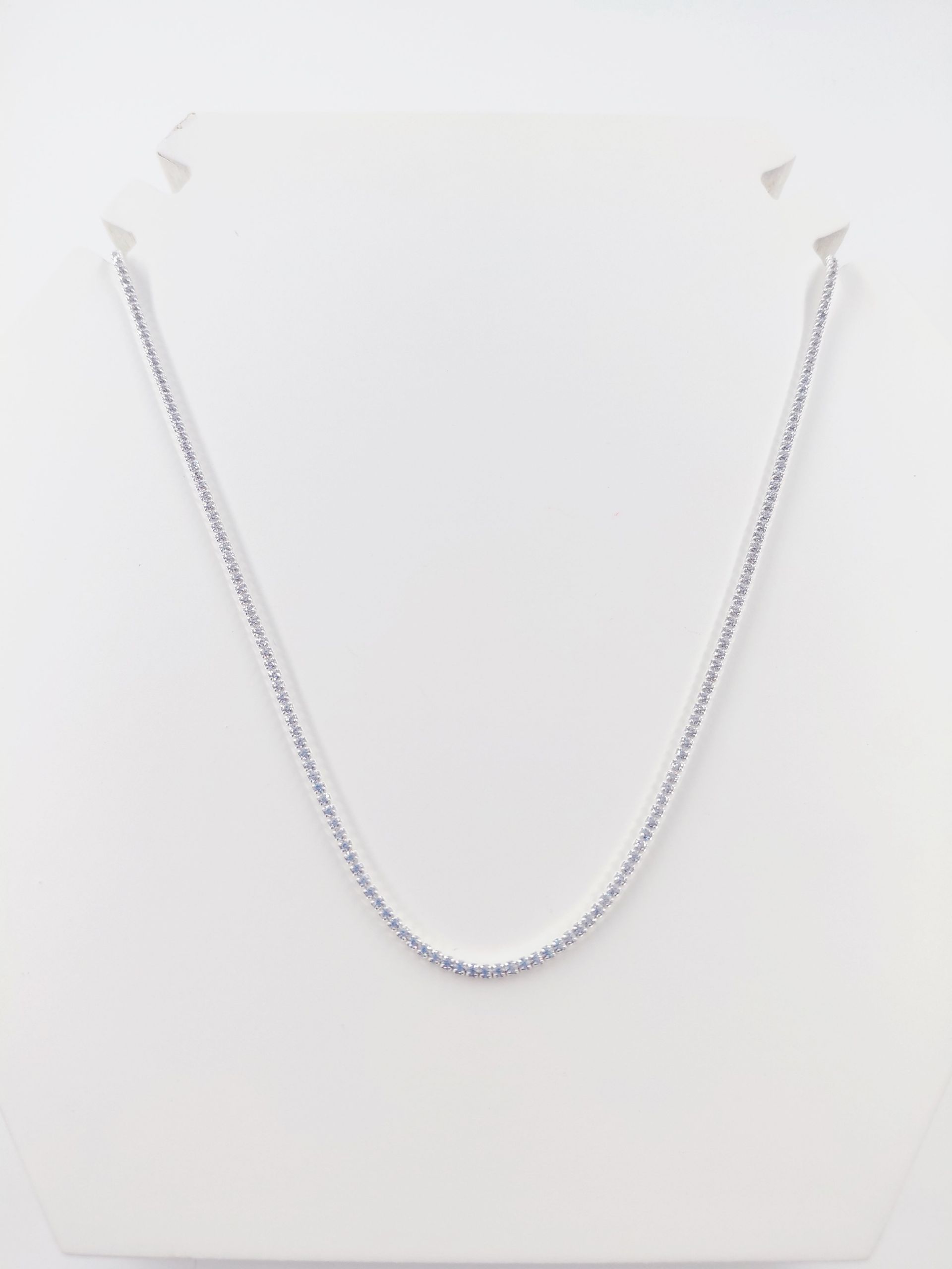 Collar de cadena de plata sobre un busto blanco de exhibición.