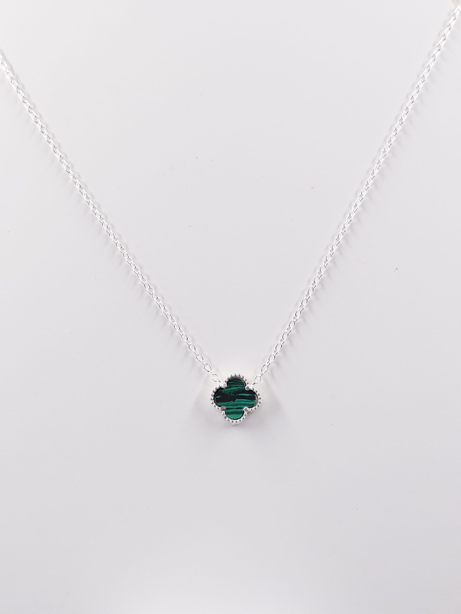Collar de plata con colgante de piedra preciosa verde sobre fondo blanco.