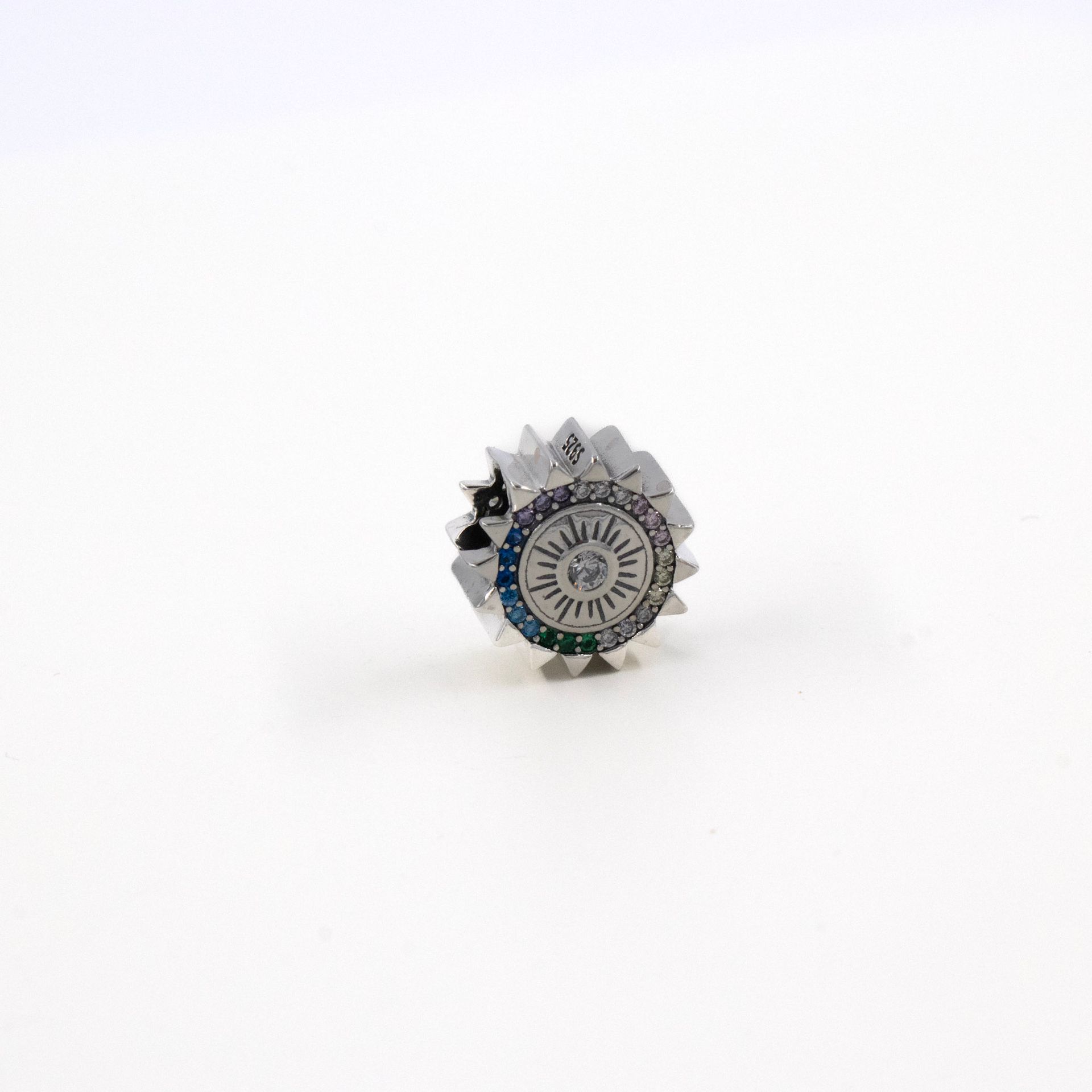 Pequeño anillo plateado con joyas sobre un fondo blanco.