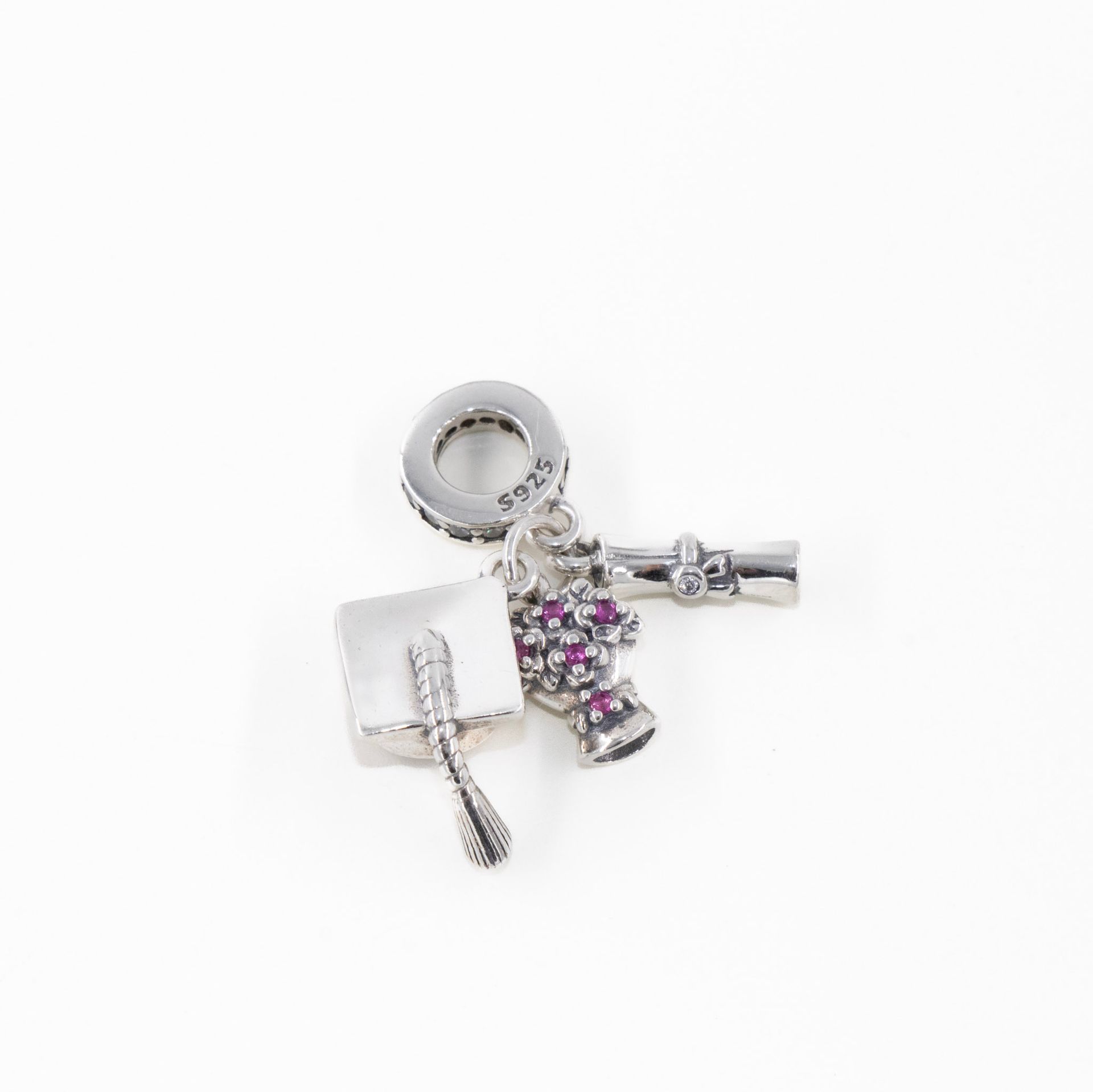 Pulsera plateada con dije de corazón de cristal, detalles en rosa y dijes colgantes de llave sobre fondo blanco.