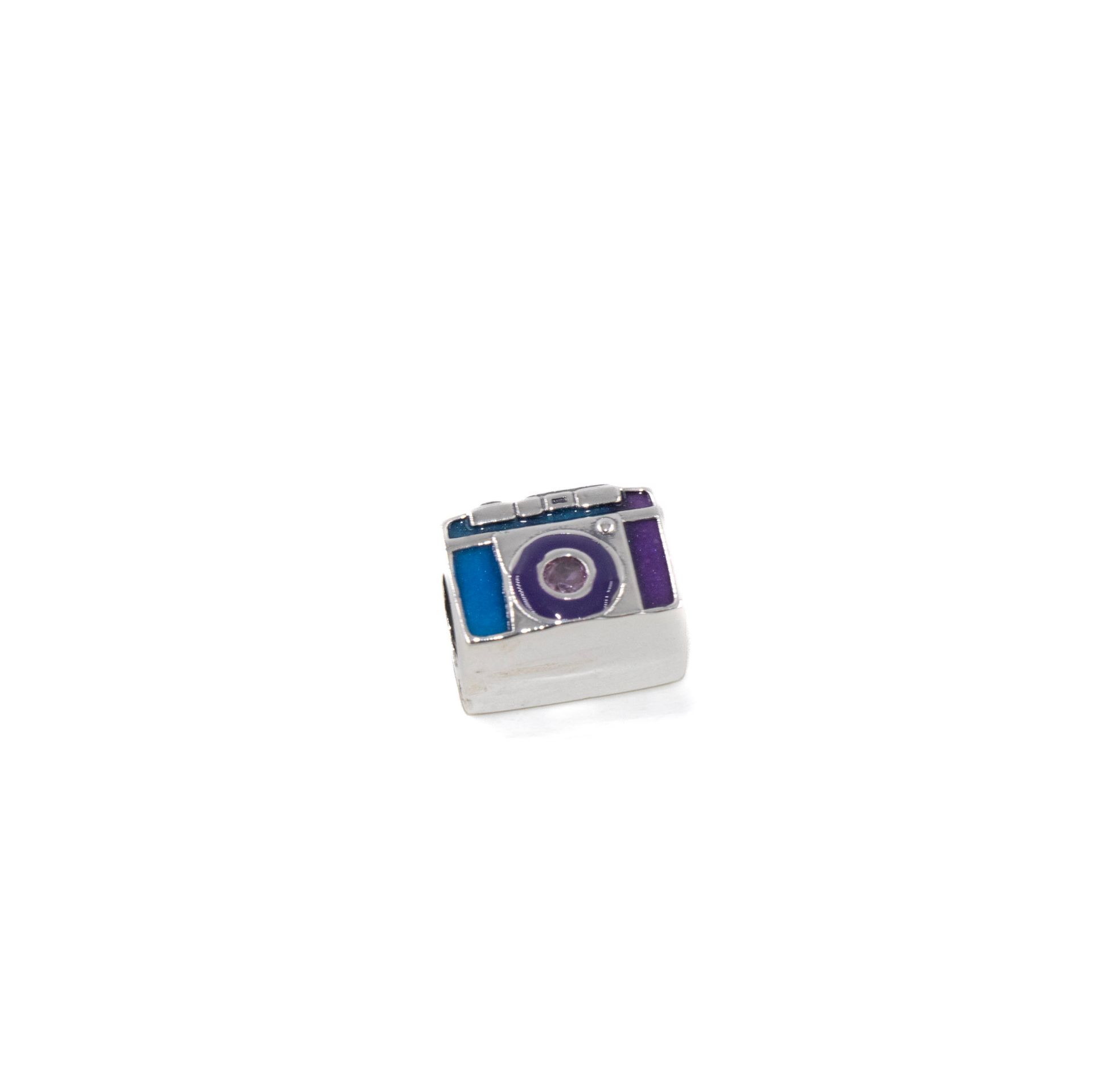 Pequeño objeto plateado y morado con forma de cámara sobre un fondo blanco.