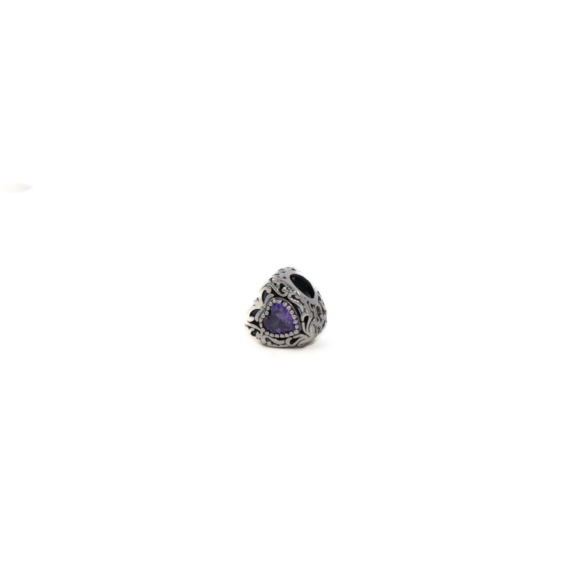 Anillo de plata con forma de corazón y una piedra preciosa morada en el centro.
