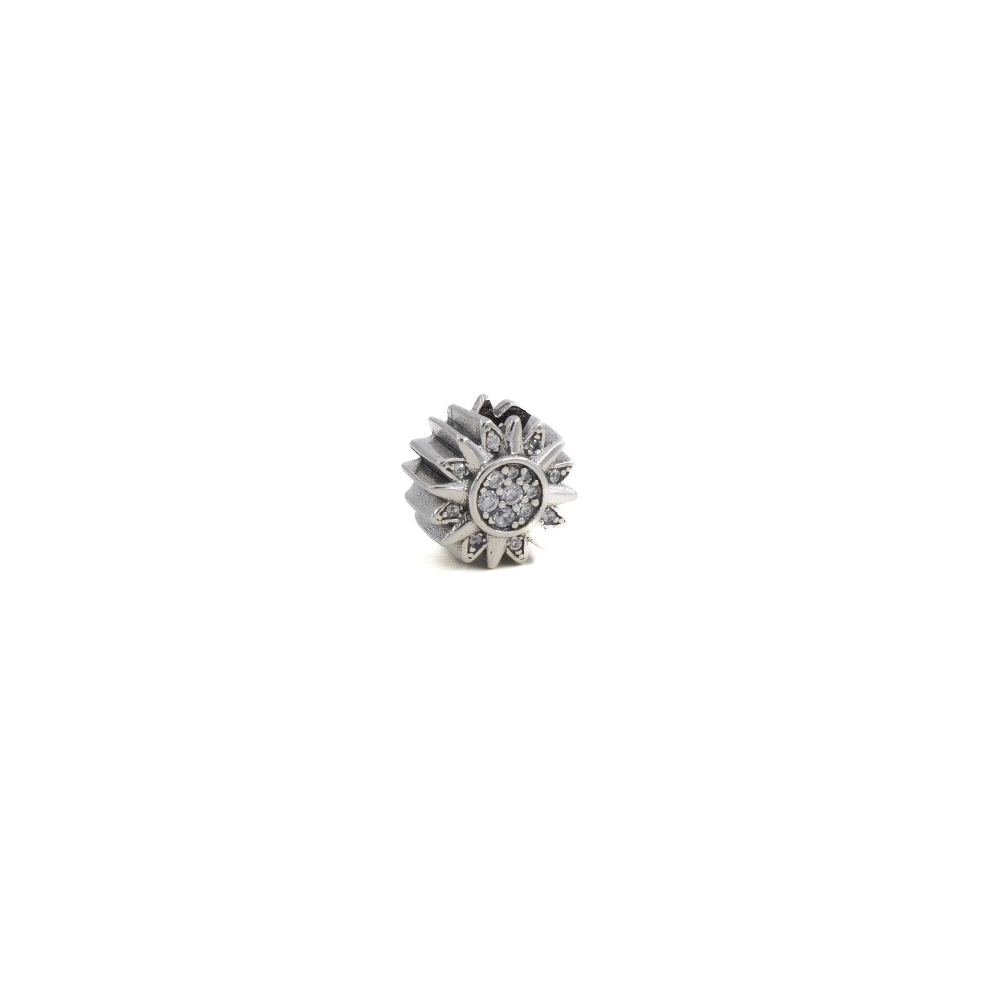 Anillo pequeño de plata con diseño floral y una piedra central transparente sobre fondo blanco.