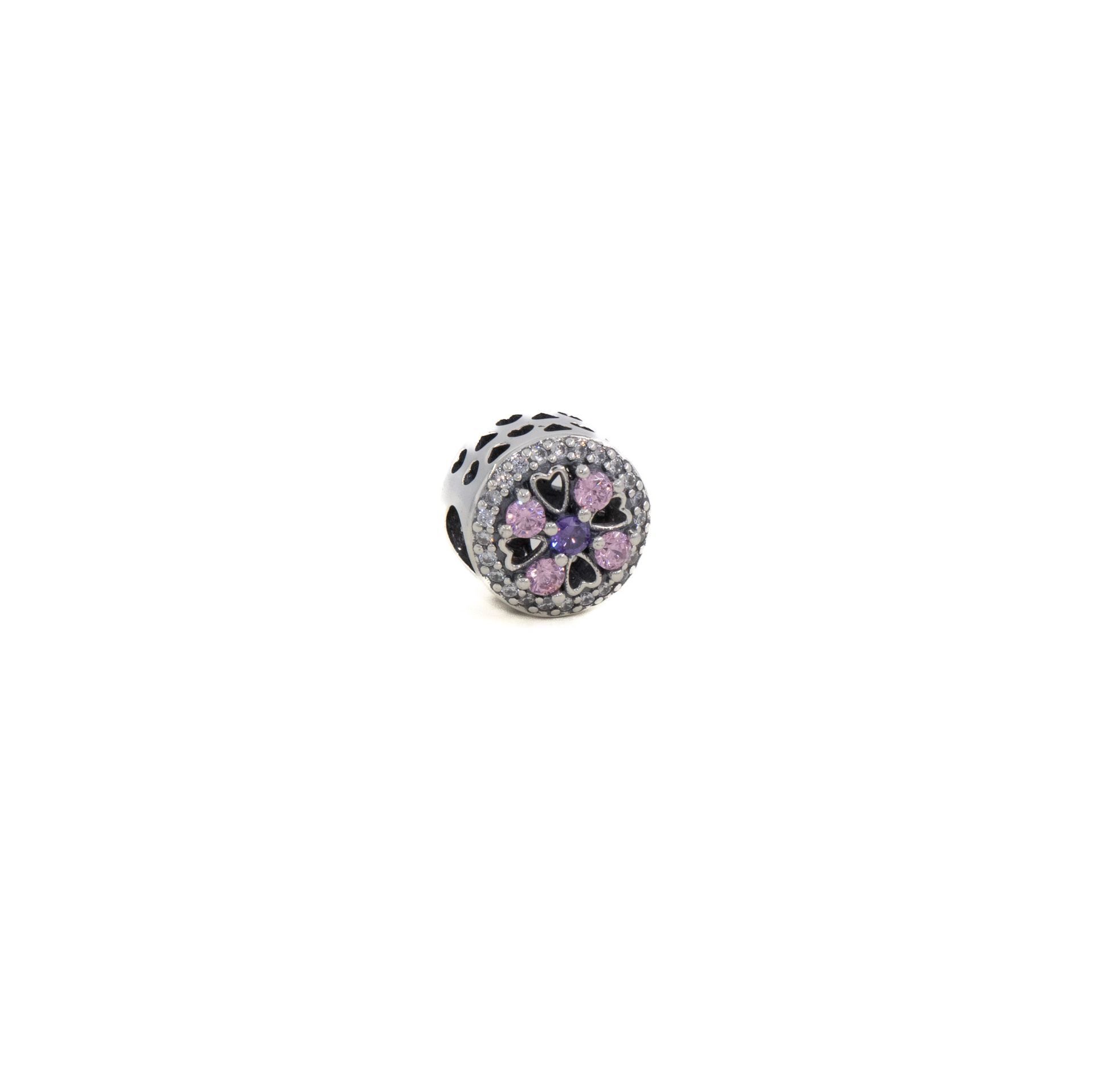 Pequeño dije redondo de plata con motivos florales negros y rosas sobre fondo blanco.