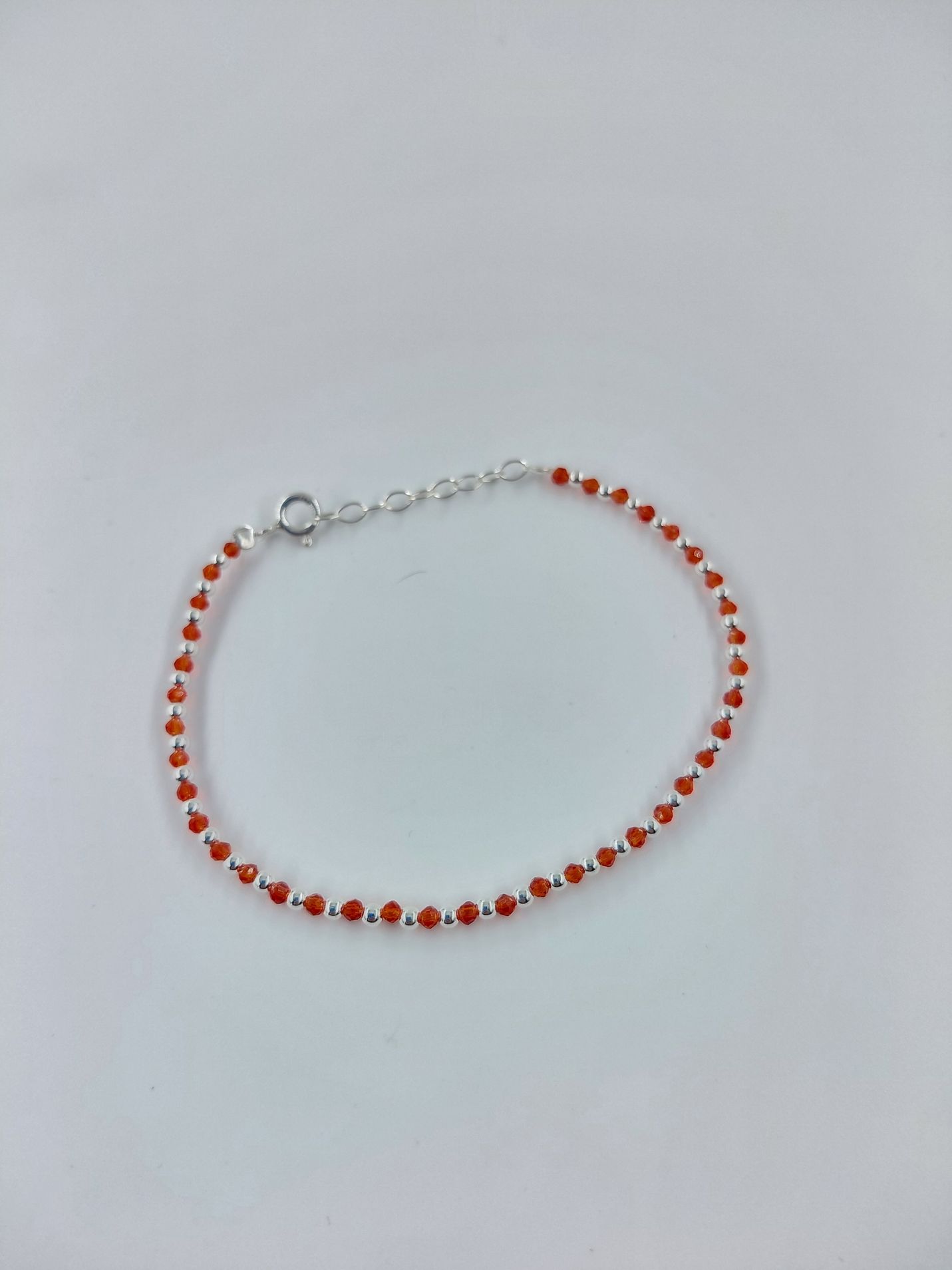 Pulsera de cuentas rojas con cierre plateado sobre fondo gris claro