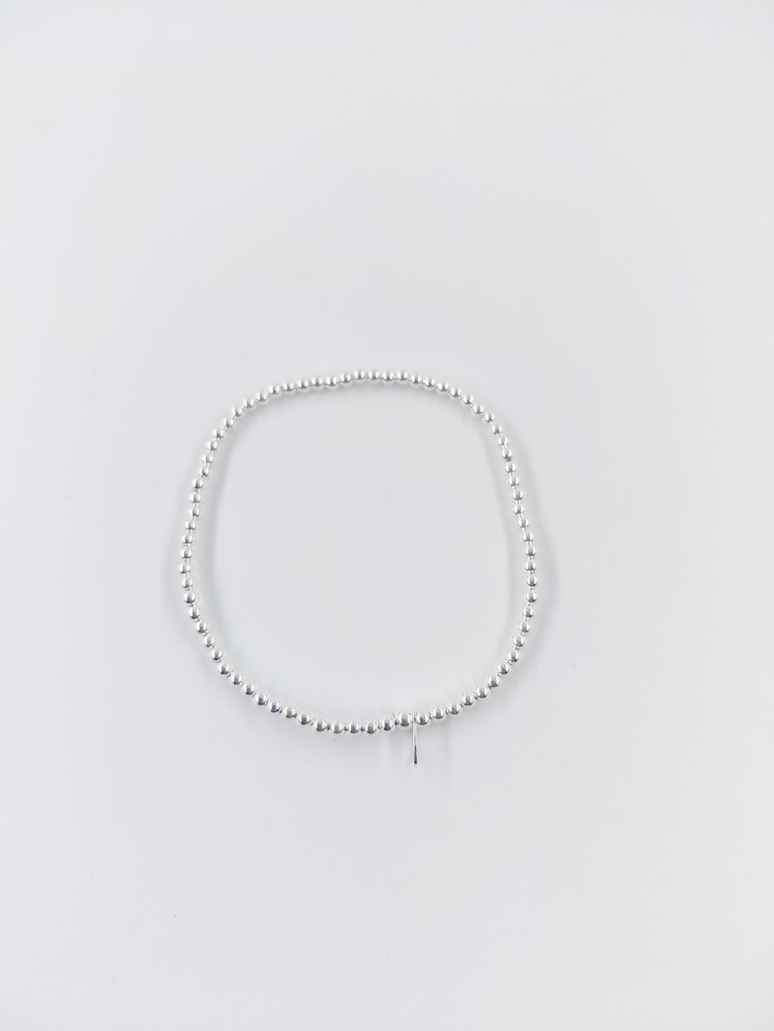 Pulsera de cuentas blancas sobre un fondo liso gris claro.